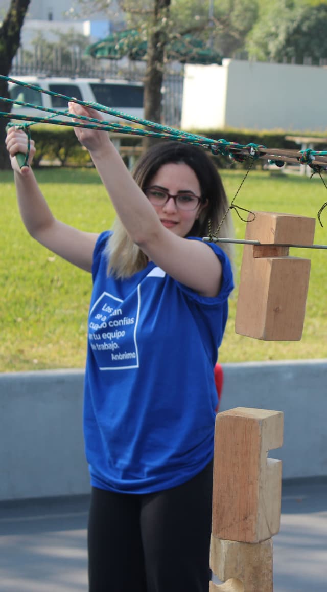 Colaboradora levantando cuerdas durante una actividad, representando el papel clave de la coordinación en Team Building